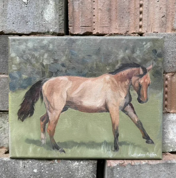 A small horse painting photographed against brick